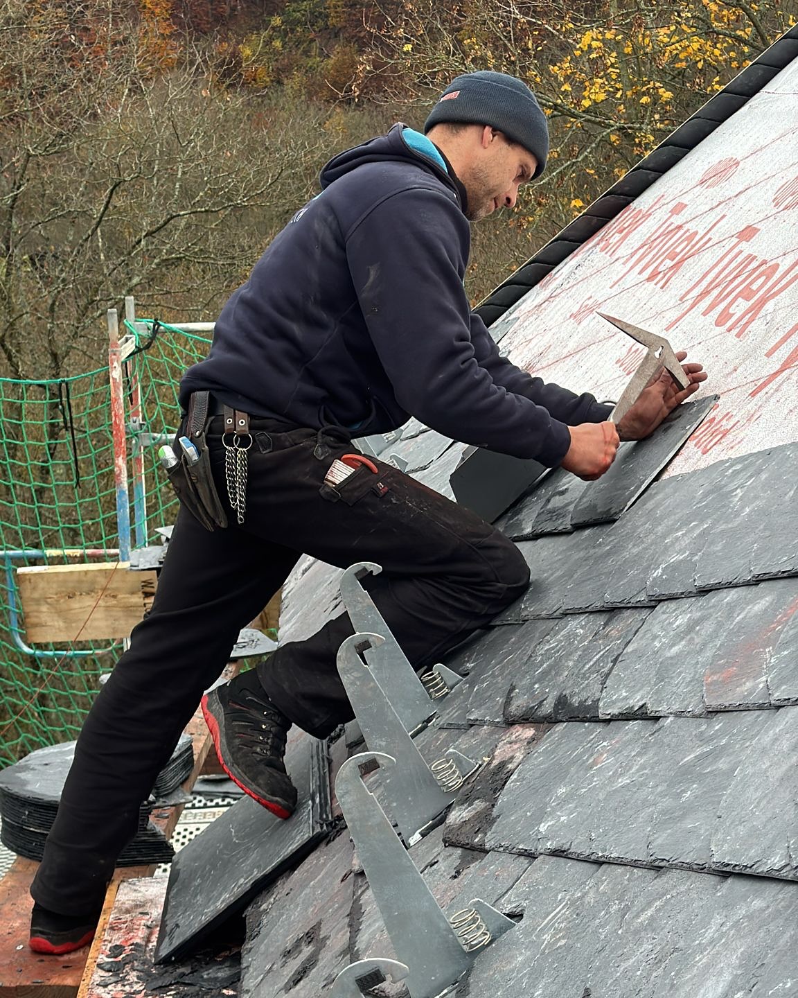 Mitarbeiter von Meyendriesch-Dach beim Verlegen von Schieferplatten auf einem Steildach mit Dachhaken – Neueindeckung im Herbst im Hunsrück