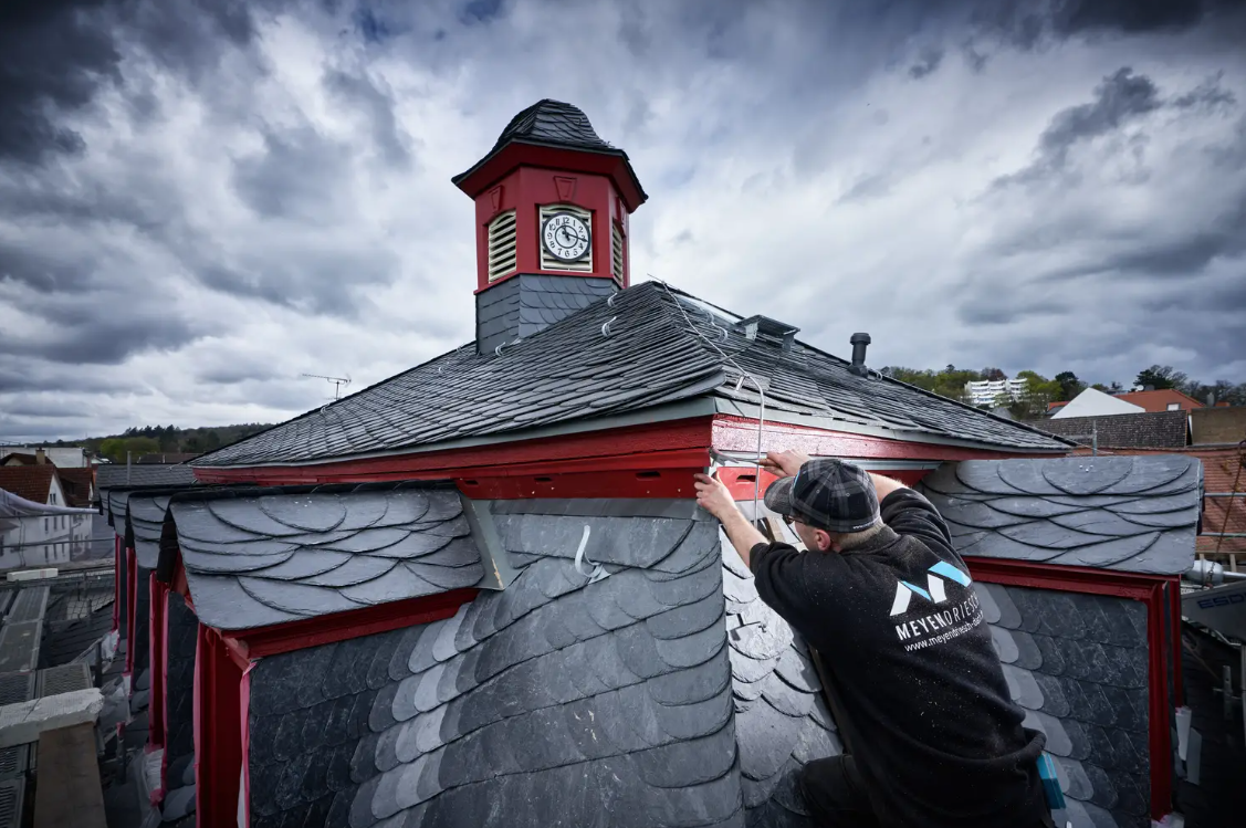 Mitarbeiter von Meyendriesch-Dach bei Detailarbeiten an der Schiefereindeckung des Alten Rathauses Bad Nauheim – Dachreiter mit Uhrenturm im Hintergrund