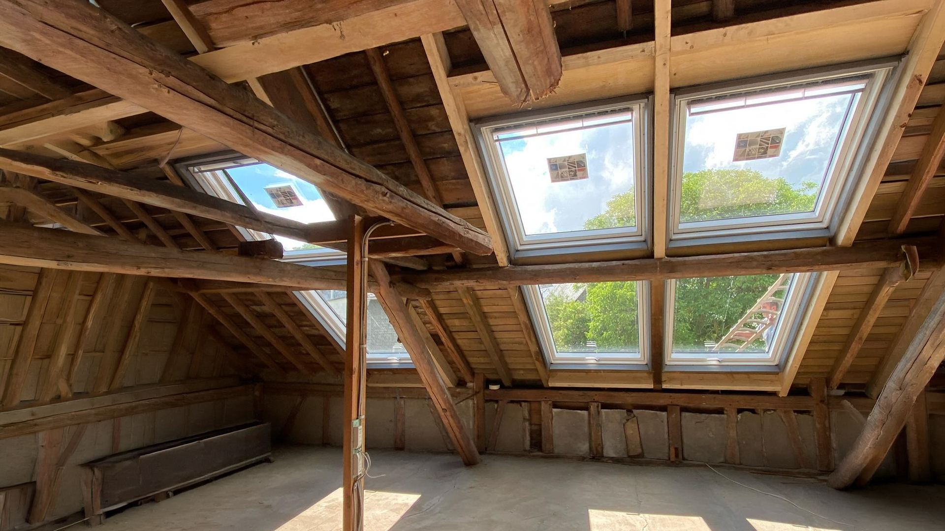 Innenansicht eines Dachbodens mit mehreren neu eingebauten Dachflächenfenstern im historischen Holzdachstuhl – Dachfenster-Montage durch Meyendriesch-Dach, Hunsrück