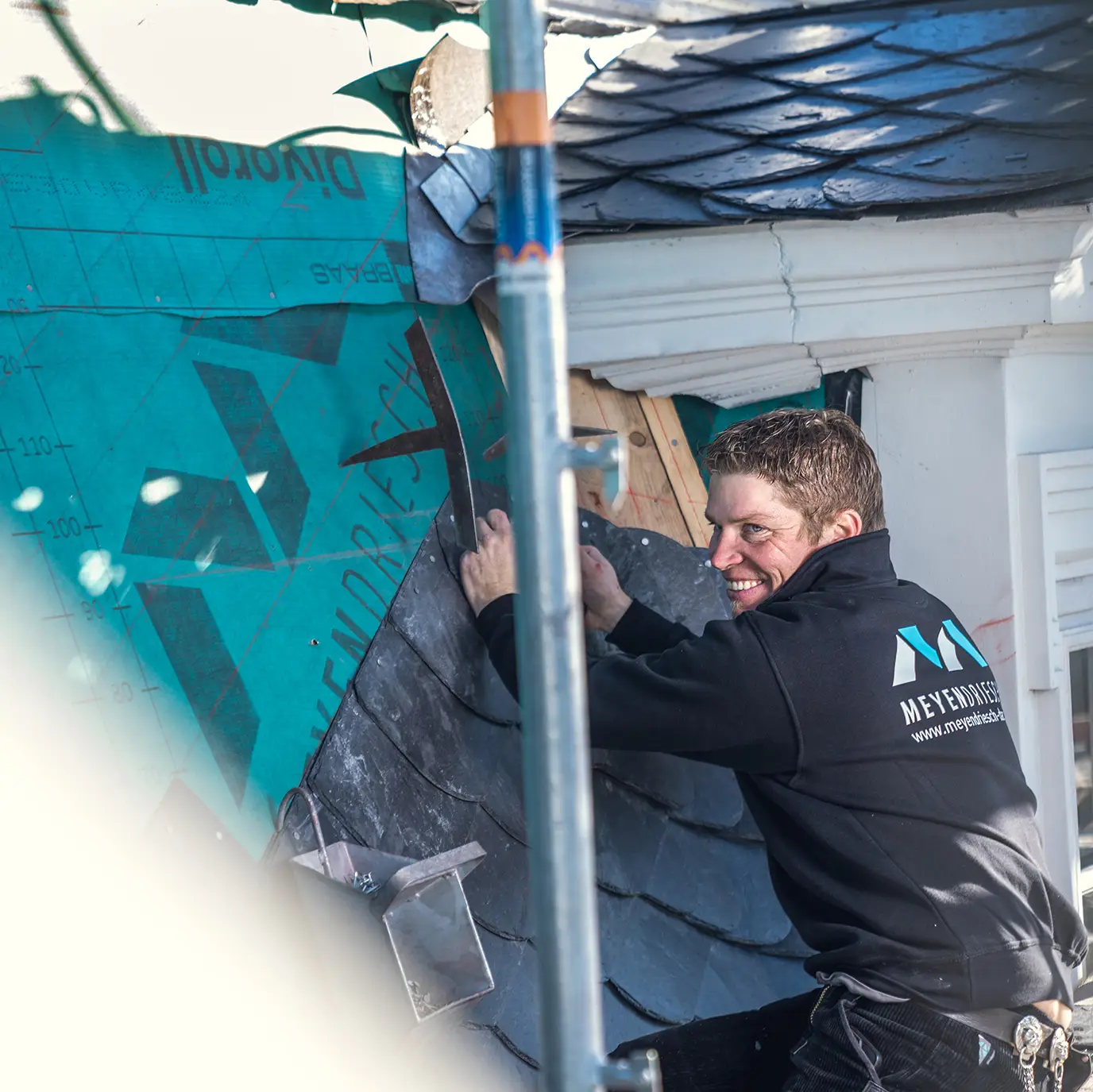 Bastian Meyendriesch, Geschäftsführer von Meyendriesch-Dach, beim Verlegen von Schieferplatten auf einer Dachbaustelle im Hunsrück
