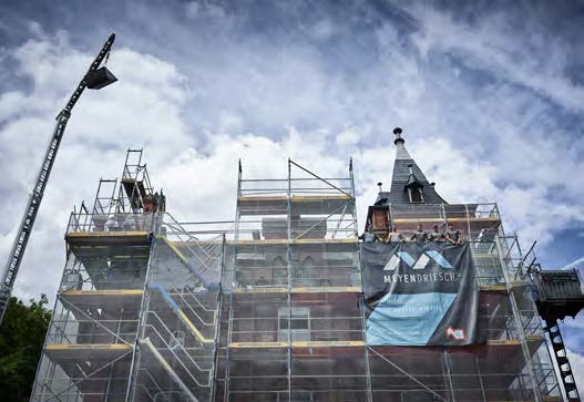 Vollständig eingerüstetes historisches Gebäude mit Meyendriesch-Banner während laufender Dachsanierung – Kran und Team im Einsatz