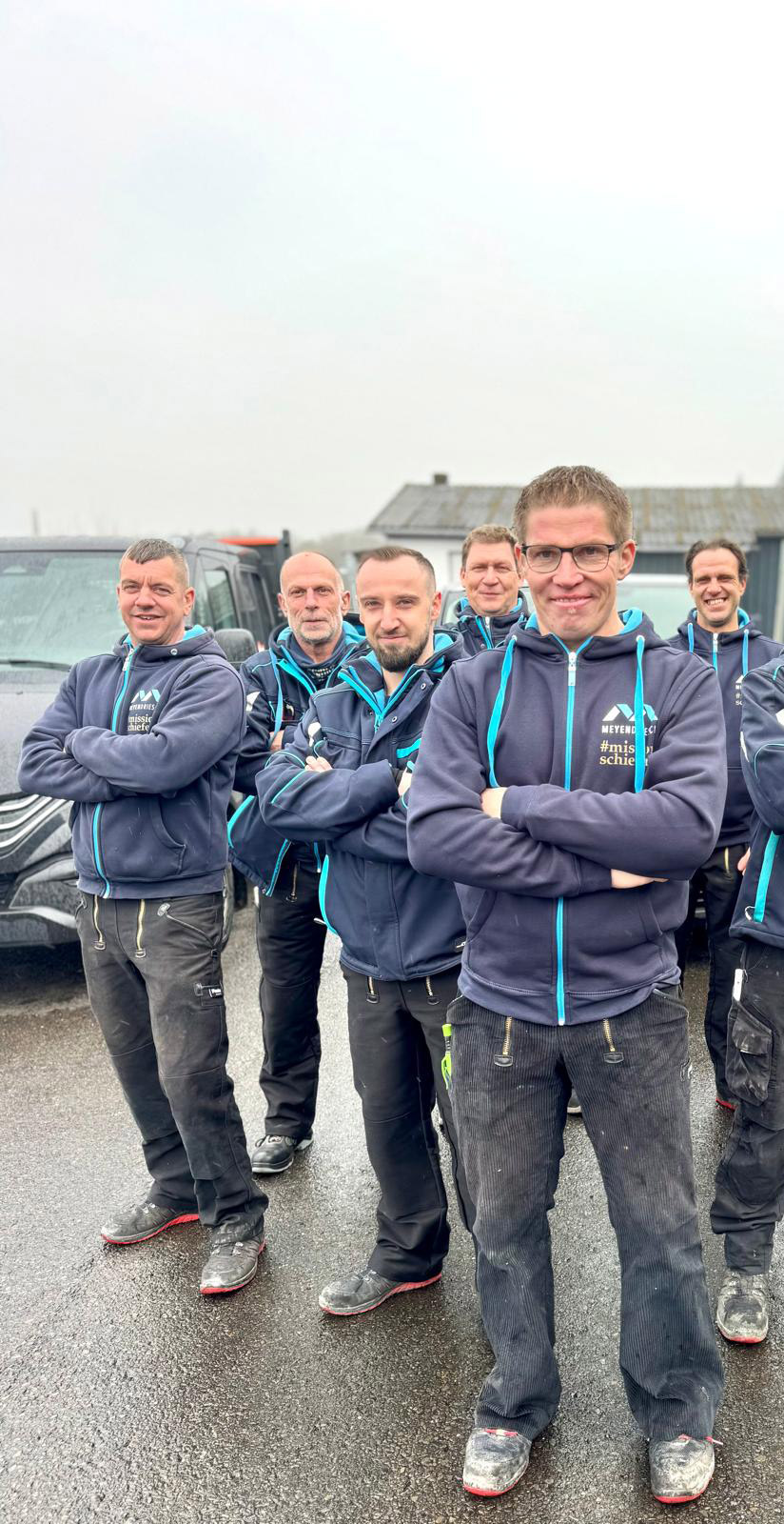 Gruppenfoto des kompletten Teams von Meyendriesch-Dach in Firmenkleidung vor den Firmenfahrzeugen – Bastian Meyendriesch im Vordergrund, Hunsrück